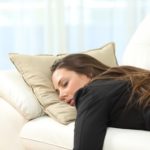 eine schlafende junge Frau auf einem weißen Sofa