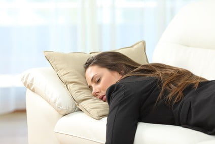 eine schlafende junge Frau auf einem weißen Sofa